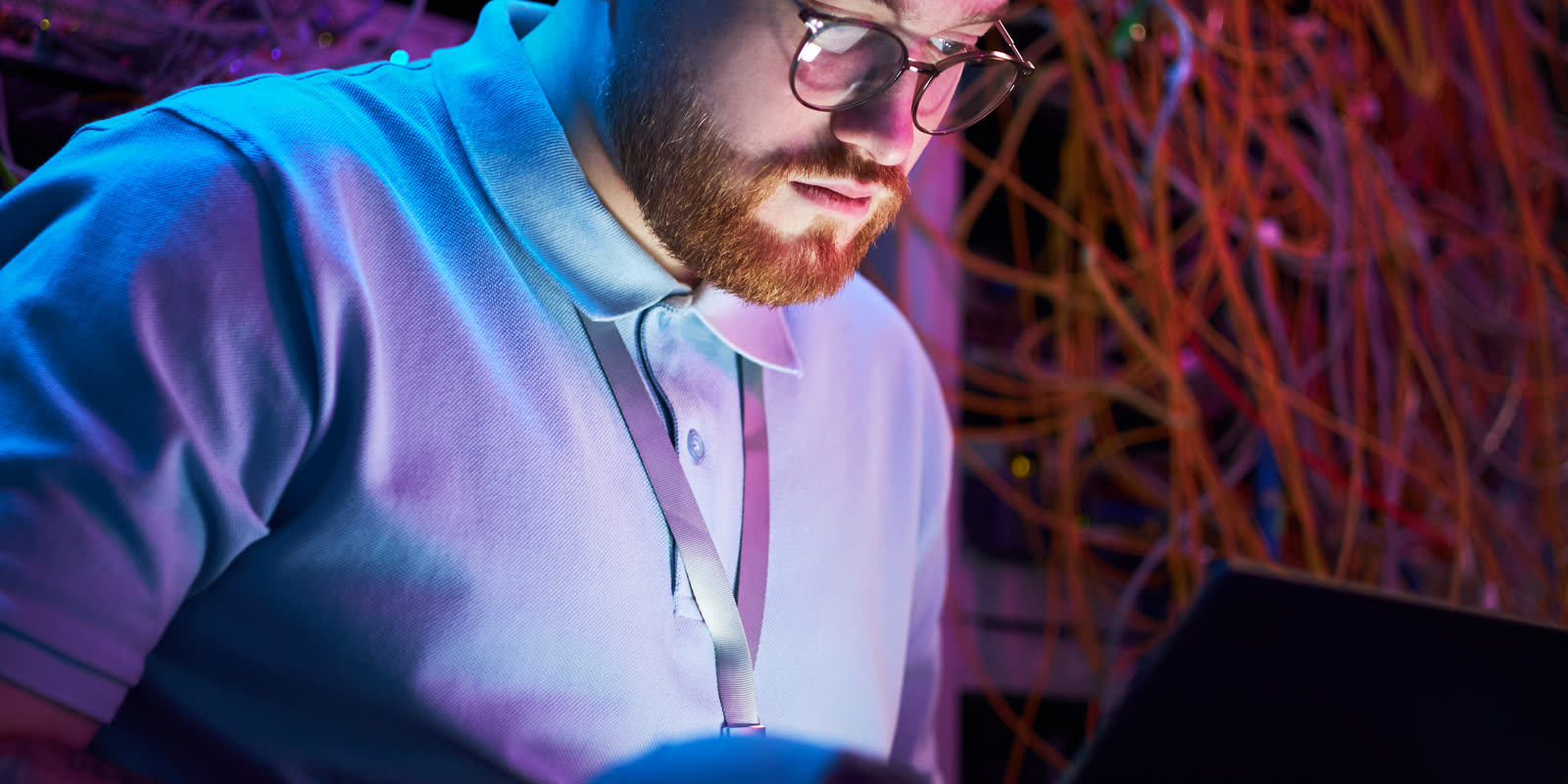Engineer on a laptop surrounded by a web of network cables